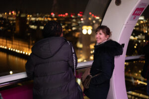 Two of Kuba's 20:30 Club members smile and look out at the city from their London Eye pod