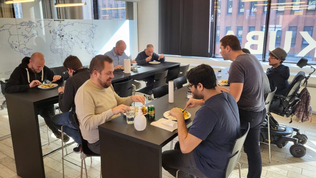 Group of men sitting at high tables eating lunch in an office