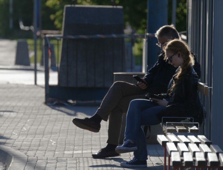 Man and girl sitting on a bench waiting for a bus