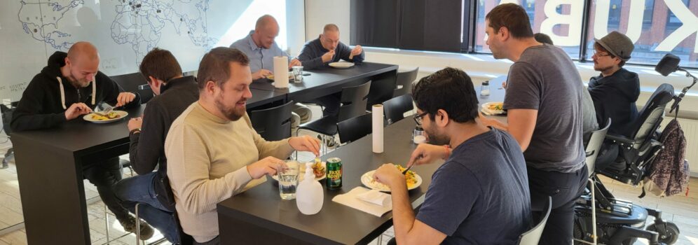Group of men sitting at high tables eating lunch in an office